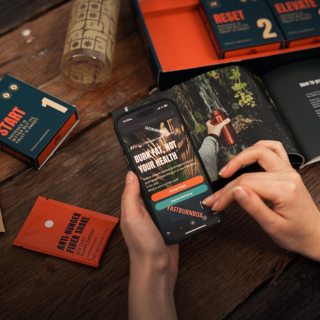 Hands holding a phone with the FastBurnBox quiz beside the opened fasting kit, guidebook and fiber shake sachet